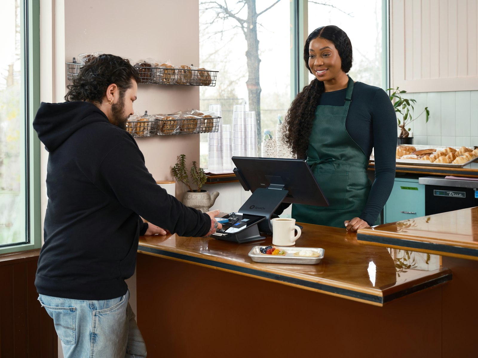 A customer paying at a café counter while the owner smiles